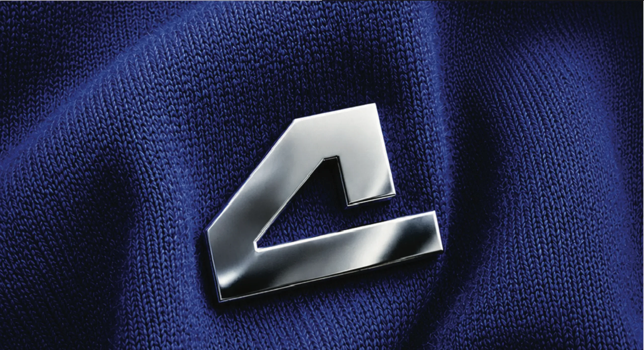 The .mp4 Productions mark as a polished metal pin on blue knit